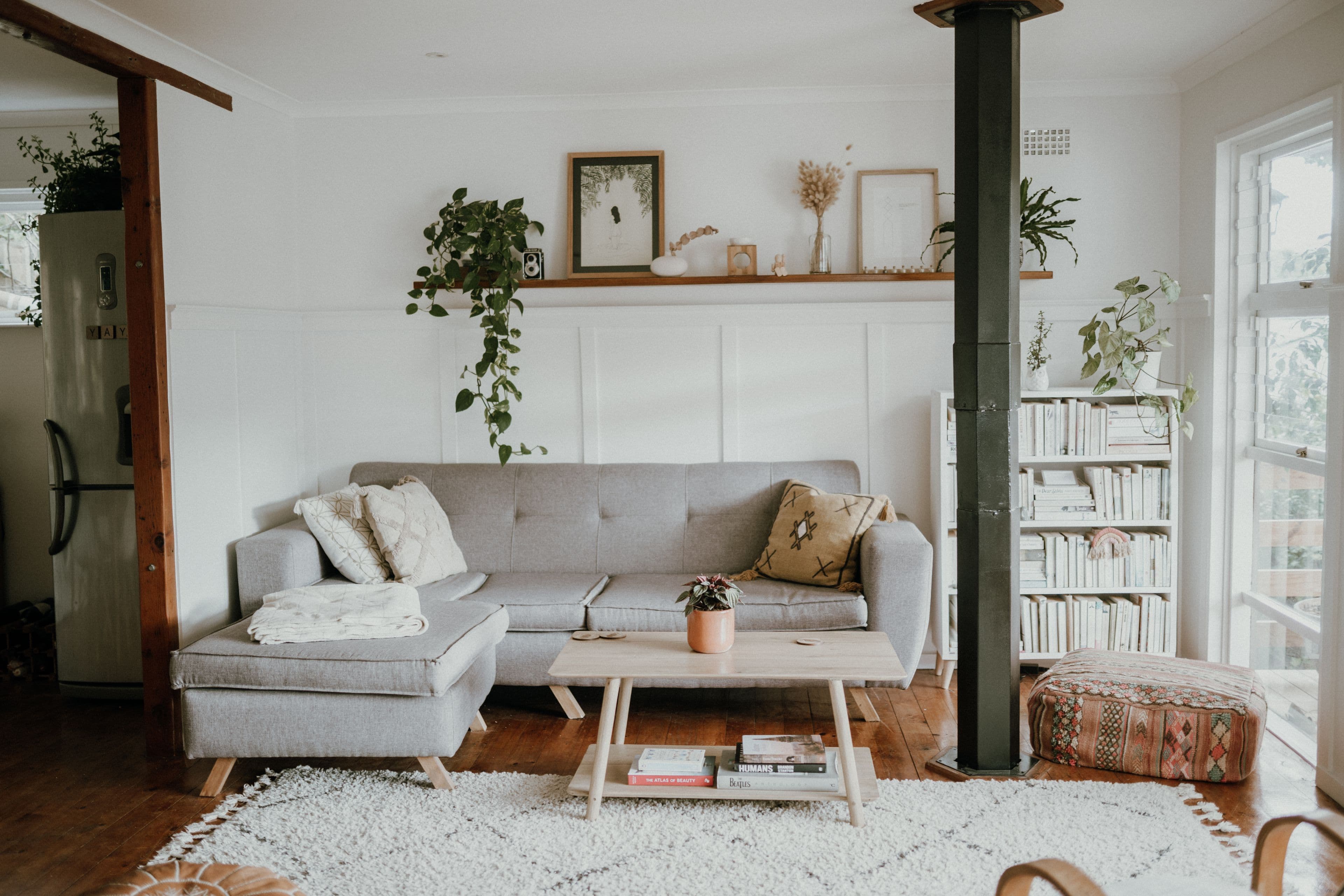 Lys stue med sofa, planter og bokhylle